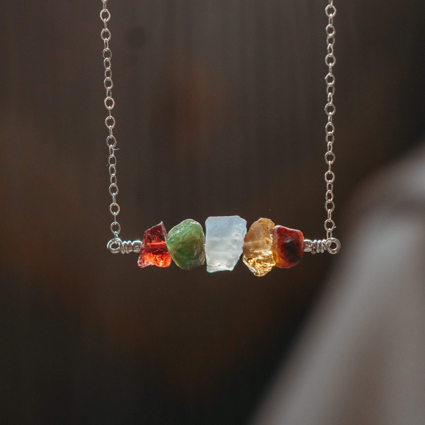 a handmade necklace with five birthstones garnet, emerald, moonstone, citrine, and ruby on sterling silver chain